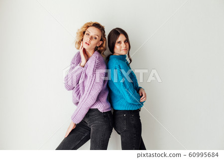 Portrait of two beautiful fashionable blonde women and a brunette in a winter sweater 60995684