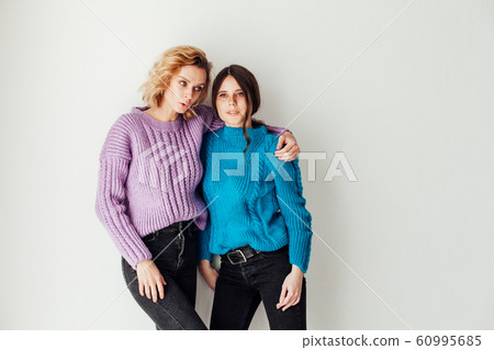 Portrait of two beautiful fashionable blonde women and a brunette in a winter sweater Portrait of two beautiful fashionable blonde women and a brunette in a winter sweater 60995685