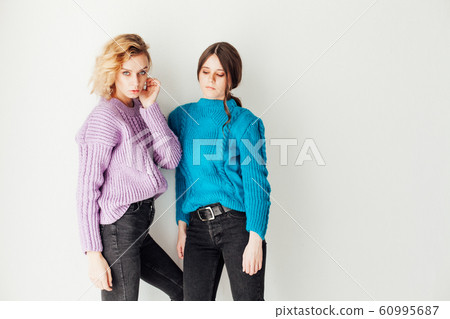 Portrait of two beautiful fashionable blonde women and a brunette in a winter sweater Portrait of two beautiful fashionable blonde women and a brunette in a winter sweater 60995687