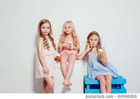 three little girls eat sweet cake with cream cupcake 60996869