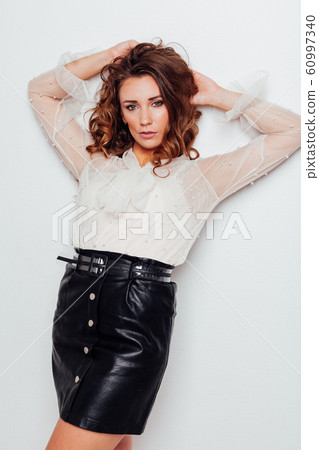 portrait of a beautiful fashionable woman with hair curls in a white blouse and black skirt portrait of a beautiful fashionable woman with hair curls in a white blouse and black skirt 60997340