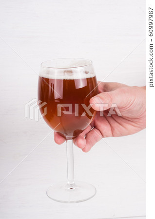 male hand holding a glass of homemade craft beer 60997987