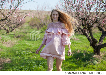 Beautiful blonde woman in pink dress in flowering garden in spring 60998030