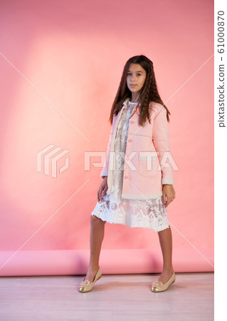 Portrait of a beautiful fashionable girl in a pink jacket and white dress 61000870