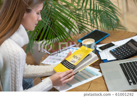 Woman learning how to pay taxes using a book 61001292
