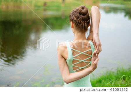 A young sports girl practices yoga on a green lawn A young sports girl practices yoga on a green lawn 61001332