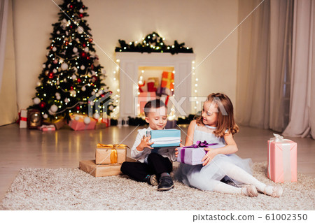 the little boy and girl open Christmas presents Christmas tree new year's Eve family celebration 61002350