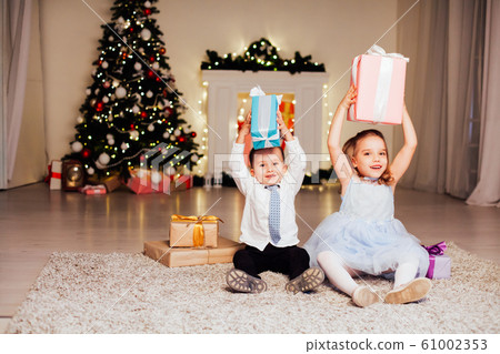 the little boy and girl open Christmas presents Christmas tree new year's Eve family celebration 61002353