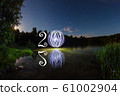 2020 written on the air with glowing ball mirrored on surface of water 61002904