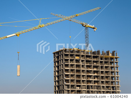 Hydraulic luffing jib tower cranes and workers being poured concrete into foundation. 61004240