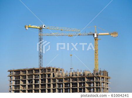 Hydraulic luffing jib tower cranes and workers being poured concrete into foundation. 61004241