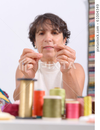 seamstress threading a needle seamstress threading a needle 61004349