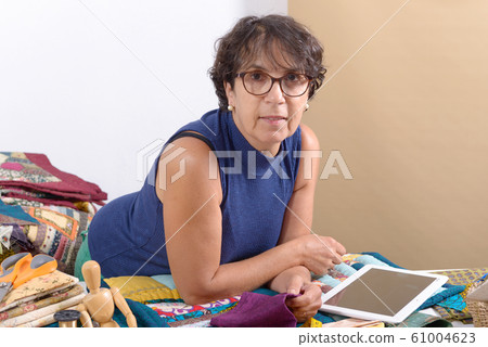 beautiful mature seamstress using tablet computer beautiful mature seamstress using tablet computer 61004623