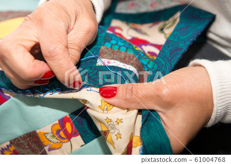 woman sewing for finish a quilt. 61004768