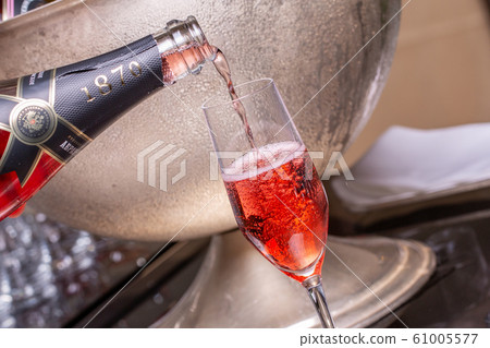 Sommelier spills pink champagne into glass 61005577