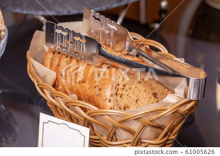 Gluten-free bread in a braided basket with tongs Gluten-free bread in a braided basket with tongs 61005626