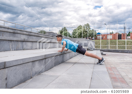 Young sportsman, male athlete, stands bar does push-ups, summer city, workout with fitness training, active lifestyle of modern youth, sportswear. Motivation for life. Free space copy text. 61005989