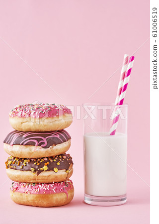 Stack of colorful donuts decorated and glass of milk 61006519