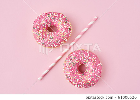 Two donuts separated with a drinking straw on pink Two donuts separated with a drinking straw on pink 61006520