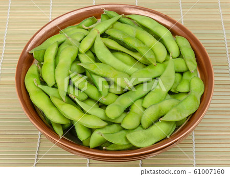 Boiled edamame, green soybeans in bowl on bamboo mat Boiled edamame, green soybeans in bowl on bamboo mat 61007160