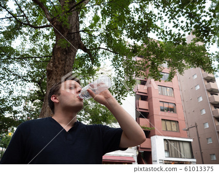 A man drinking water from a plastic bottle 61013375