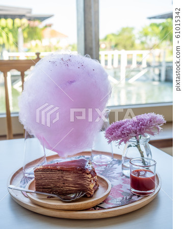 A piece of strawberry jam crepe cake on wooden round plate 61015342