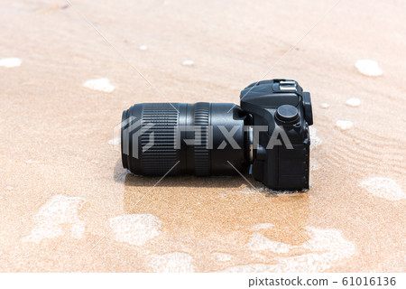 DSLR camera on beach wet from water sea wave DSLR camera on beach wet from water sea wave 61016136