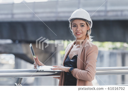 close up portrait young beautiful woman engineer white helmet standing. close up portrait young beautiful woman engineer white helmet standing. 61016702