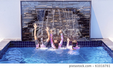 Three Young Girls Playing Under A Pool Waterfall Three Young Girls Playing Under A Pool Waterfall 61018781