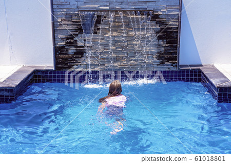 Young Girl Swims Towards A Splashing Fountain Young Girl Swims Towards A Splashing Fountain 61018801