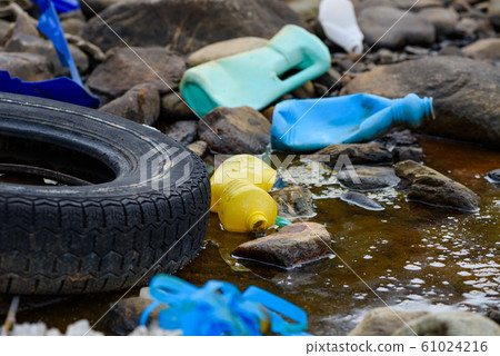 Enviromental pollution. Rubber tire with plastic waste in dirty water. Enviromental pollution. Rubber tire with plastic waste in dirty water. 61024216