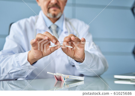 Doctor's hands holding a broken cigarette, healthy lifestyle concept 61025686