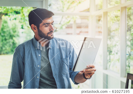 A man looking at paper note while working A man looking at paper note while working 61027195