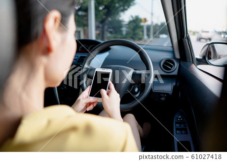 Young woman in car checking her smartphone while Young woman in car checking her smartphone while 61027418