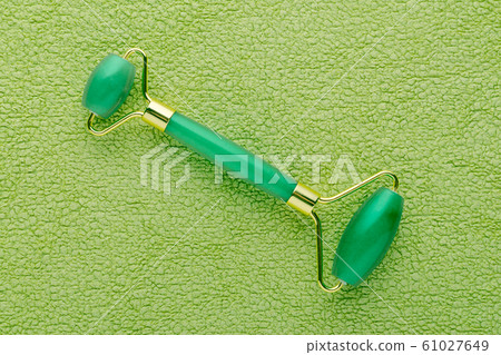 real jade facial roller on green background, flat lay real jade facial roller on green background, flat lay 61027649