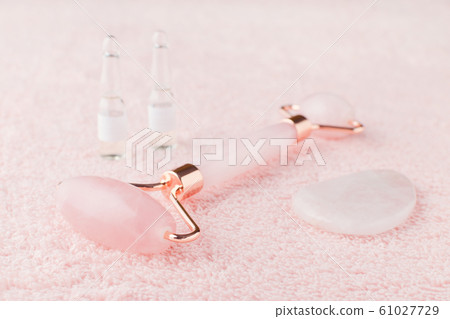 real rose quartz facial roller, gua sha massage stone and face serum in ampoules, selective focus real rose quartz facial roller, gua sha massage stone and face serum in ampoules, selective focus 61027729