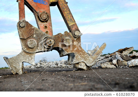Excavator with hydraulic shears breaks asphalt on a construction site. Excavator with hydraulic shears breaks asphalt on a construction site. 61028070