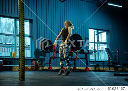 Caucasian teenage girl practicing in weightlifting in gym Caucasian teenage girl practicing in weightlifting in gym 61028467