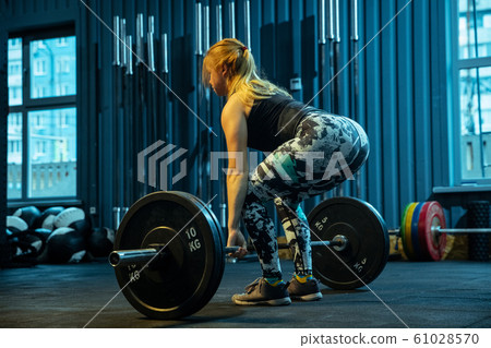 Caucasian teenage girl practicing in weightlifting in gym Caucasian teenage girl practicing in weightlifting in gym 61028570