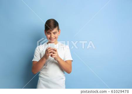 Caucasian teen's portrait isolated on blue studio background Caucasian teen's portrait isolated on blue studio background 61029478