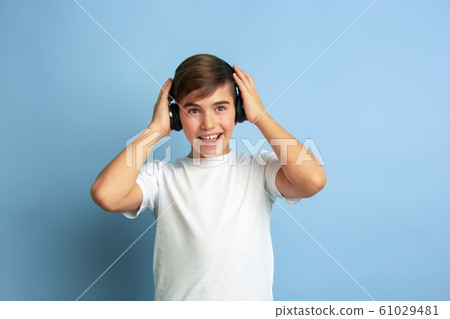 Caucasian teen's portrait isolated on blue studio background Caucasian teen's portrait isolated on blue studio background 61029481