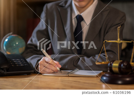 Justice and law concept.Male judge in a courtroom the gavel, working with digital tablet computer on wood table. 61036196