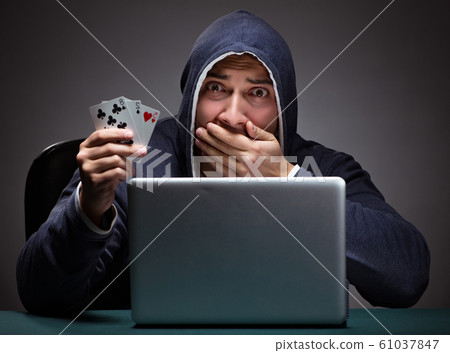 Young man wearing a hoodie sitting in front of a laptop computer Young man wearing a hoodie sitting in front of a laptop computer 61037847