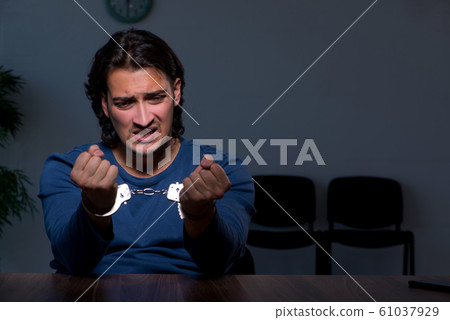 Young convict man sitting in dark room Young convict man sitting in dark room 61037929