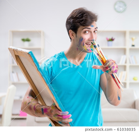 Young funny artist working on new painting in his studio 61038035