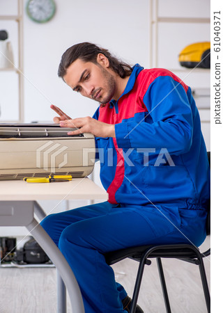 Young male contractor repairing air-conditioner at workshop 61040371
