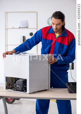 Young male contractor repairing refrigerator at workshop Young male contractor repairing refrigerator at workshop 61040415