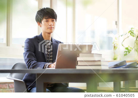 Young man operating a laptop Young man operating a laptop 61040505