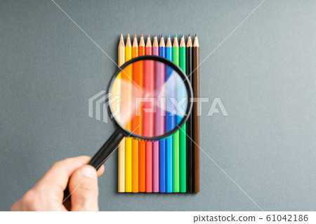 magnifier in hand over colored pencils magnifier in hand over colored pencils 61042186