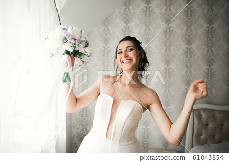 Gorgeous bride in robe posing and preparing for the wedding ceremony face in a room Gorgeous bride in robe posing and preparing for the wedding ceremony face in a room 61043854